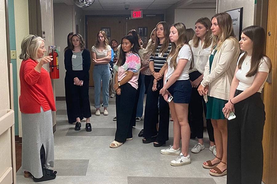 Students standing in a hospital hallway attend orientation. 