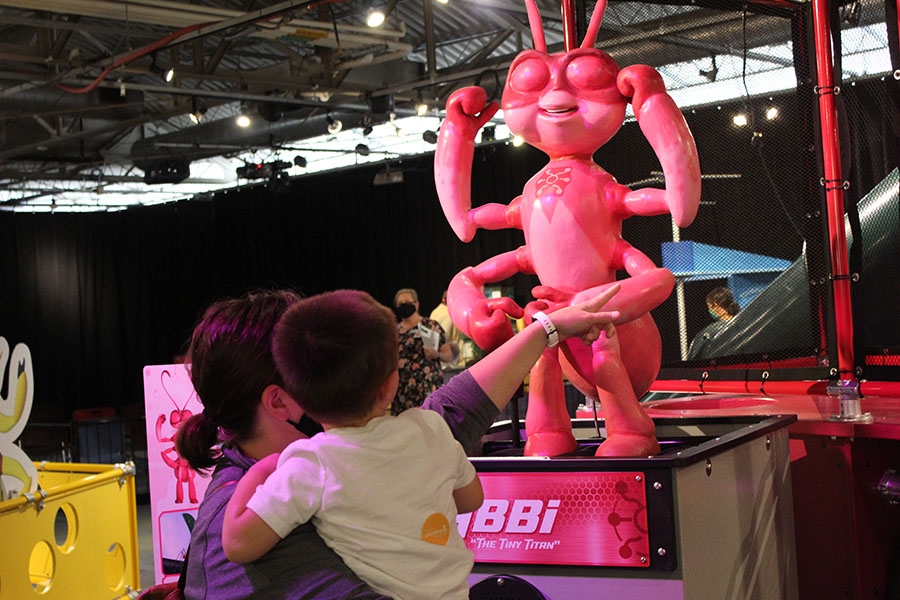 An adult holding a child looking at an animatronic bug.