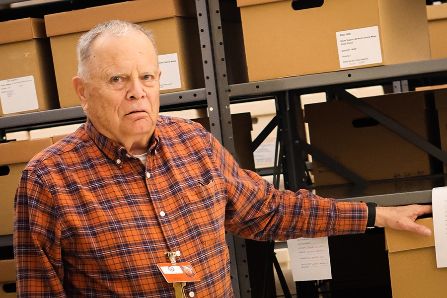 Gerald Franklin standing in front of a shelving unit with his hand on a tan storage box.