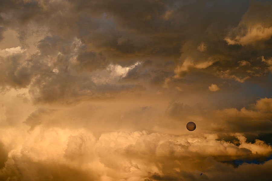 A weather balloon soaring into a sunset.