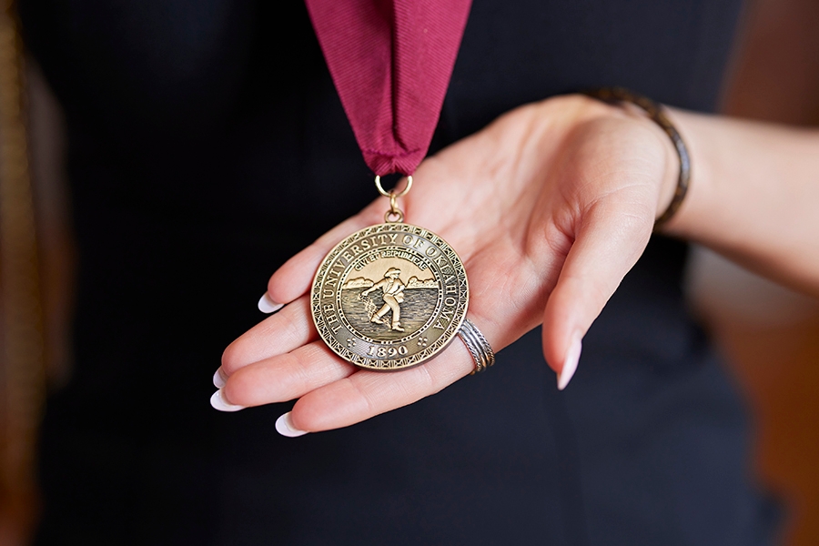 OU graduate holding 4.0 medallion.
