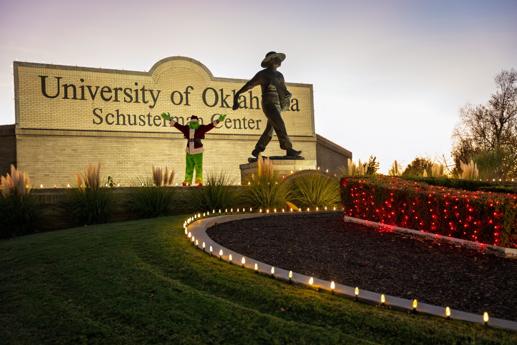 The Grinch standing behind the Seed Sower statue. 