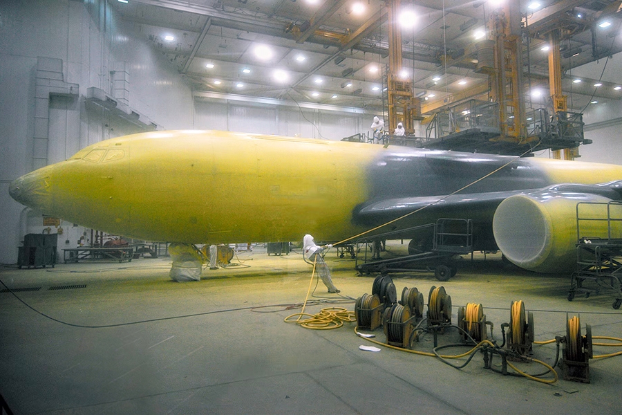 A military plane being painted with yellow primer.