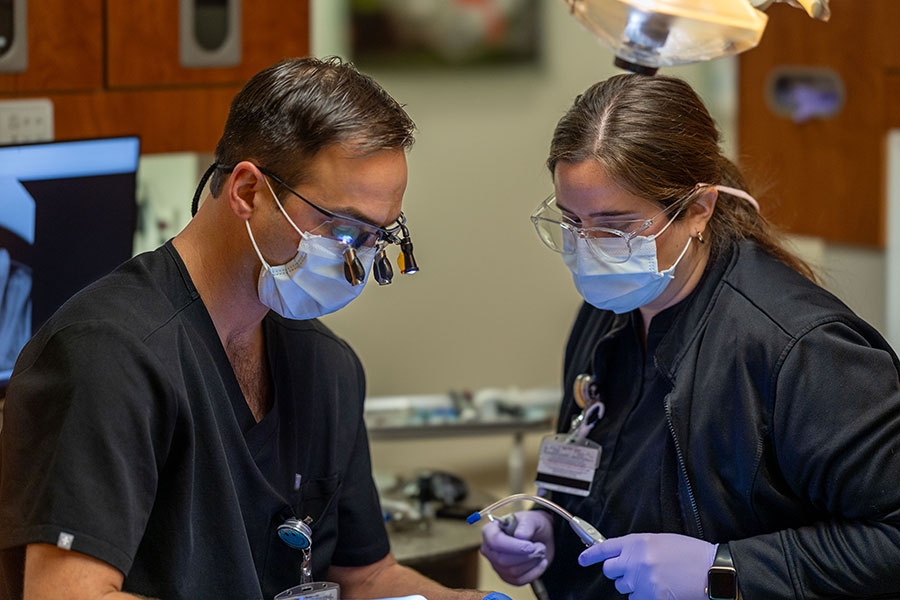 Two dentists looking down at a patient out of frame.