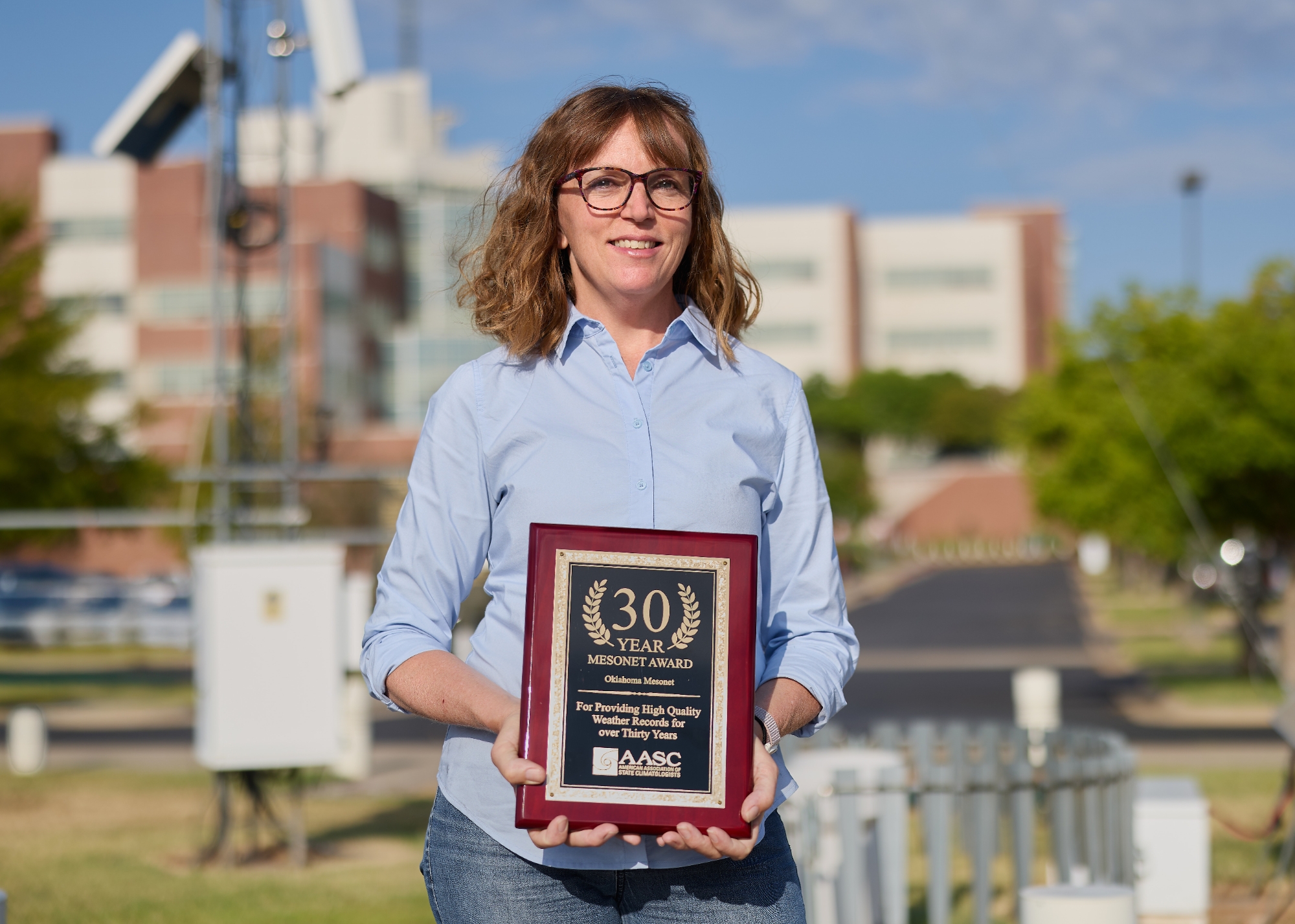 Cindy Luttrell holds the plaque honoring the Mesonet's 30 years of service. 