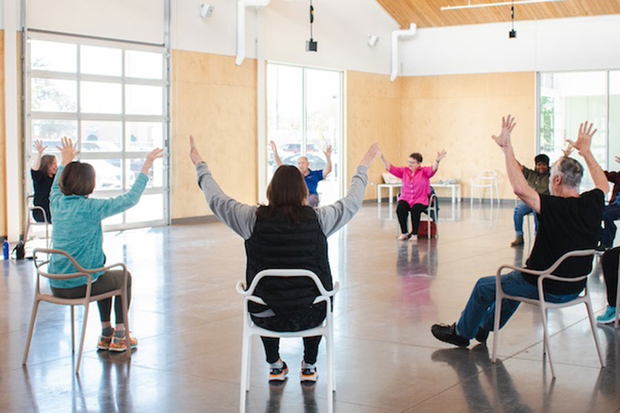 Individuals sitting in chairs raise their arms.
