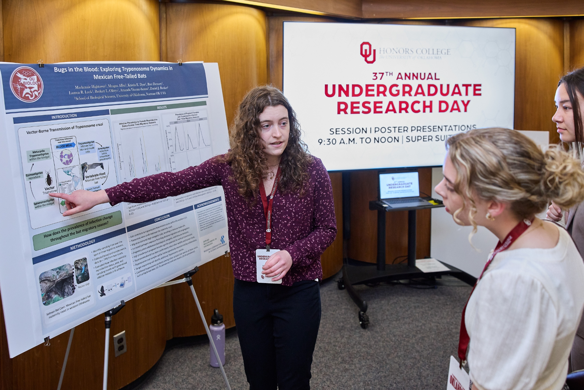 A student pointing at their poster presentation.