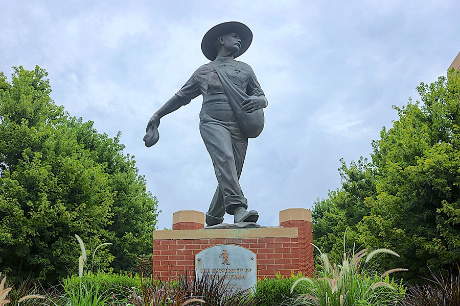 Photo of a statue of a man, with greenery surrounding the statue.