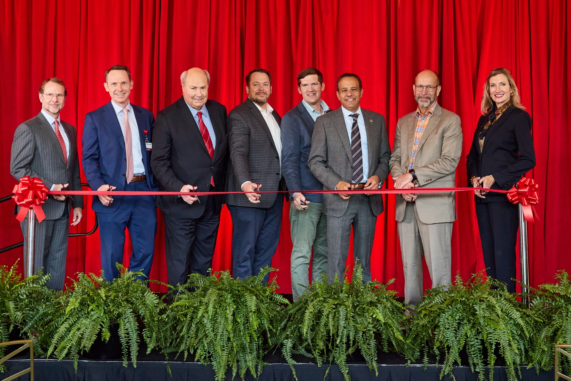 A line of people cutting a red ribbon.