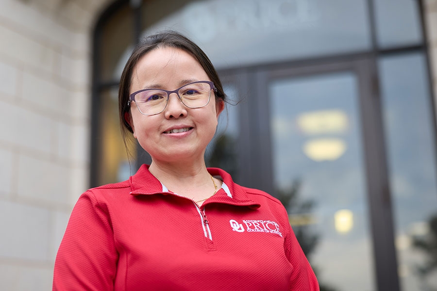 University of Oklahoma professor Qiong Wang stands outside Price College building.