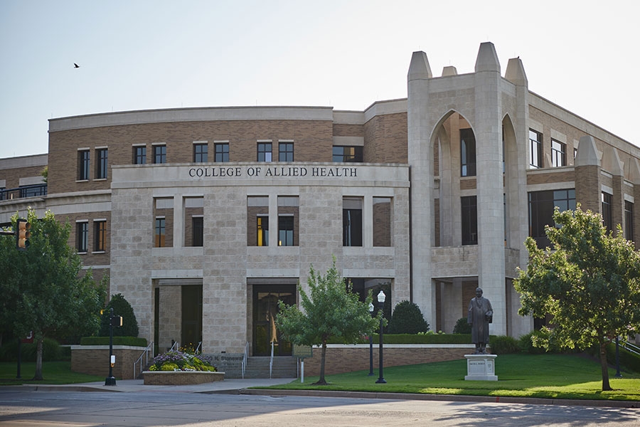 Outdoor entrance of multi-story building with inscription "College of Allied Health."