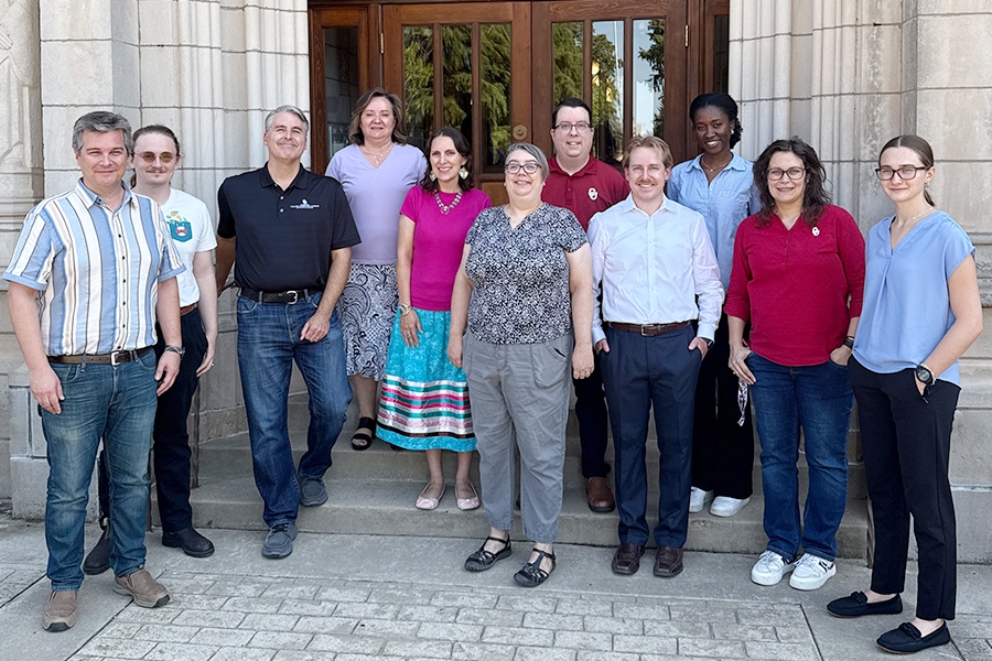 The research team standing as a group on the stairs outside of a campus building.