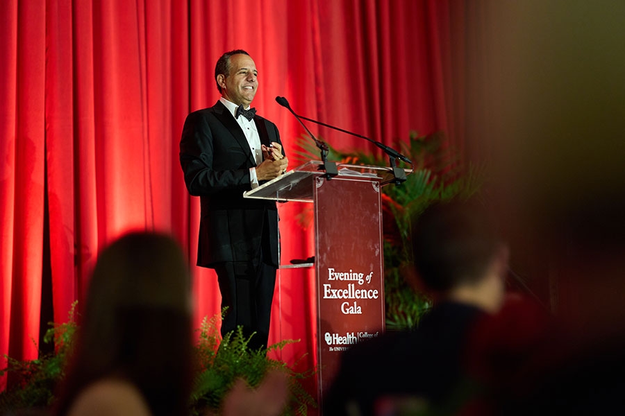 Joseph Harroz standing at a podium in front of a red curtain.