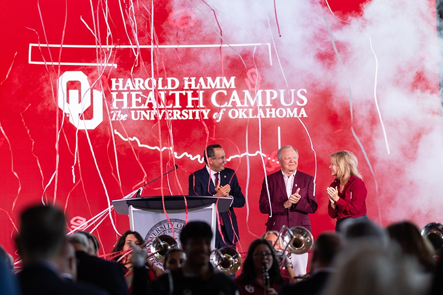 OU President Joseph Harroz Jr., Harold Hamm, and Shelly Lambertz standing on a stage.