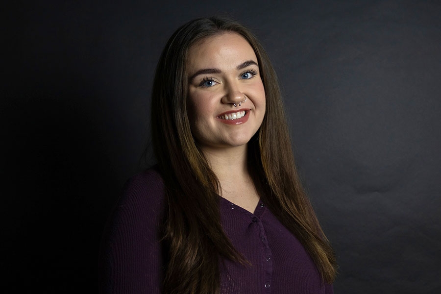 Woman smiling in front of black background.