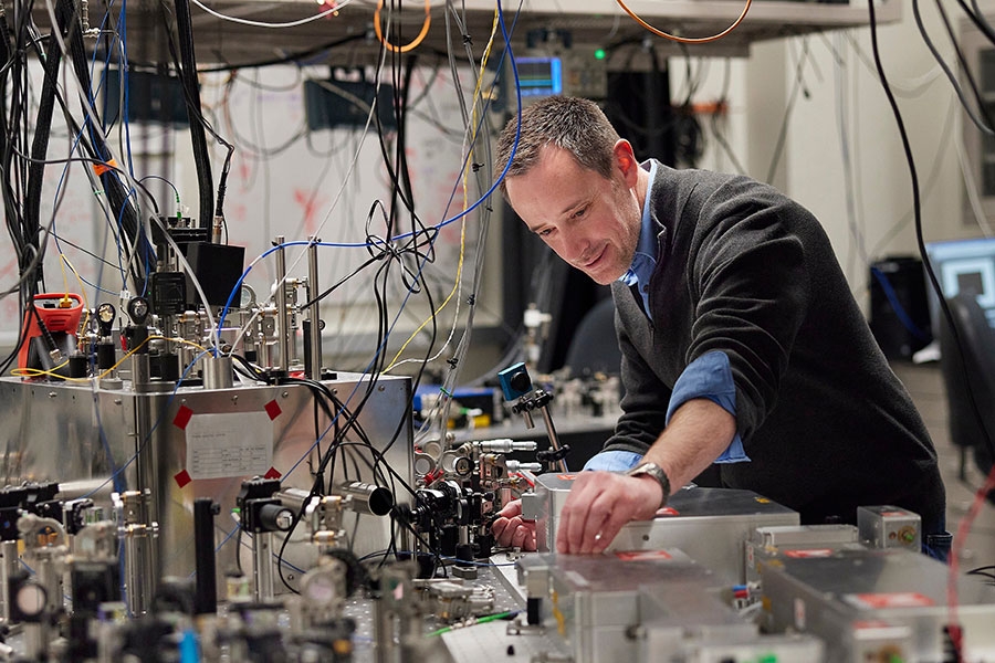 A man bending over technology in a lab.