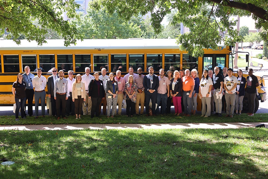 Group of adults standing next to Shawnee Public Schools electric bus