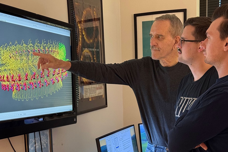 Image of Dr. Rodney Tweten pointing at a screen alongside two OU doctoral students.