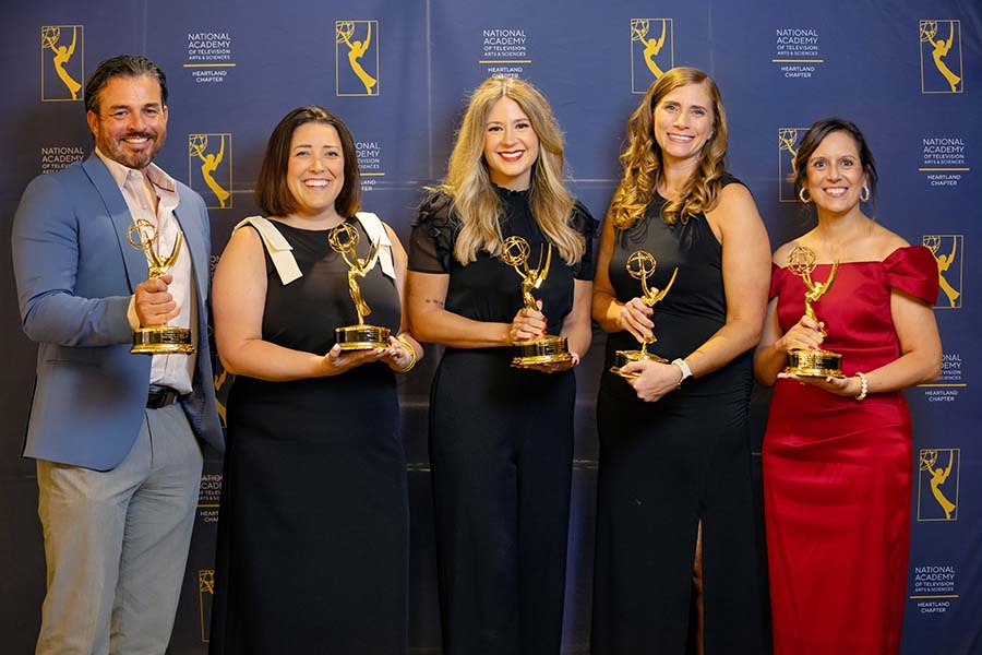 Five people pose with Emmy trophies.