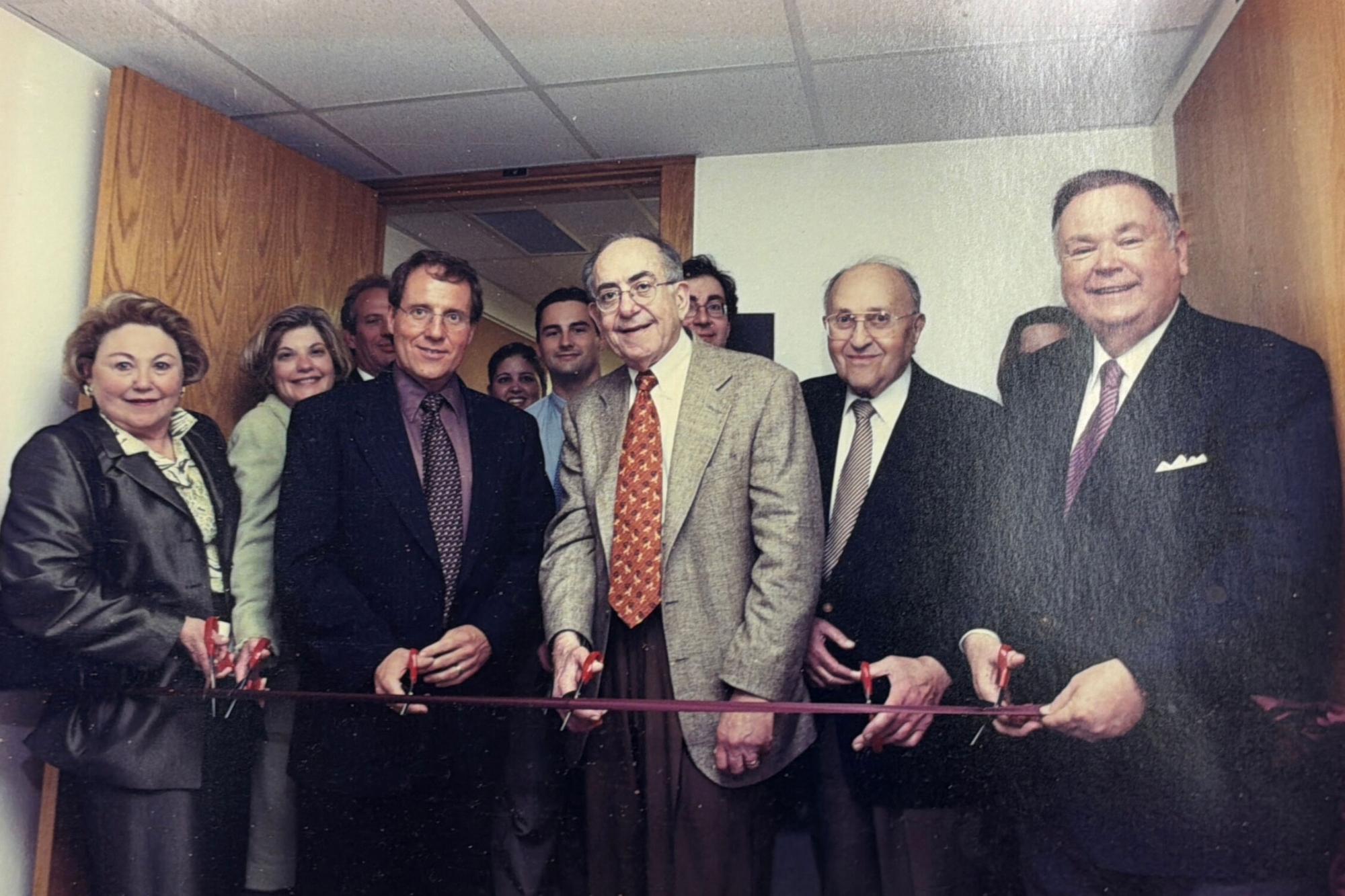 A group of people cutting a red ribbon.