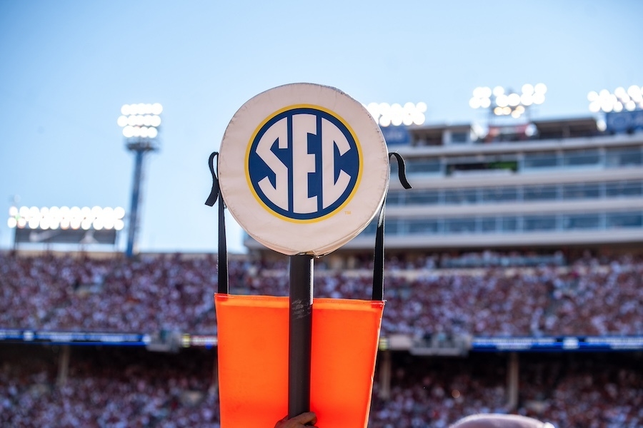 The SEC logo with a football stadium behind it.