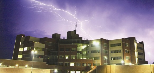The sky above the National Weather Center is illuminated by lightning during a nighttime thunderstorm.