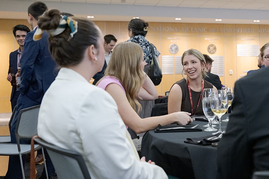 People sitting at a table at an event in the National Weather Center Atrium.