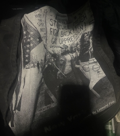 A black and white photograph of the Stonewall riots printed on a tote bag is visible in the picture.