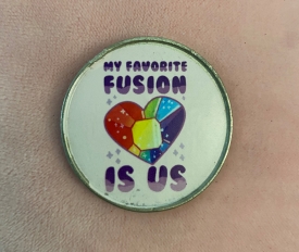 A circular pin on a beige background that reads, "My favorite fusion is us." At the center of the pin and text is the image of a jeweled, rainbow-colored heart.