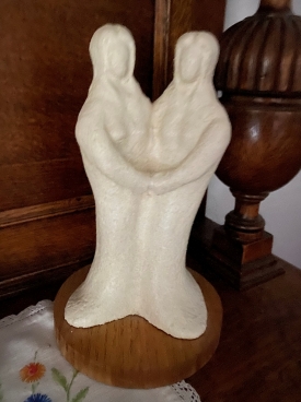 A white statue of two women holding each other