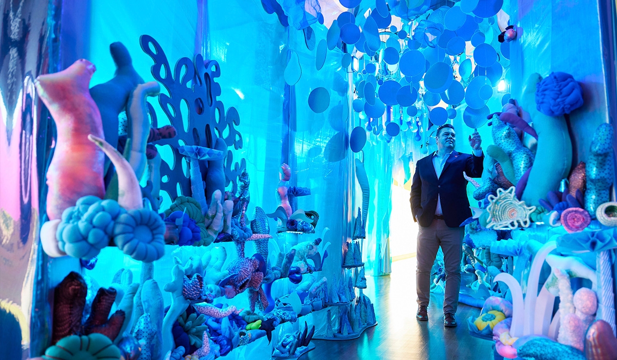 A man standing in front of a tunnel-like art display, exuding a sense of curiosity and anticipation.