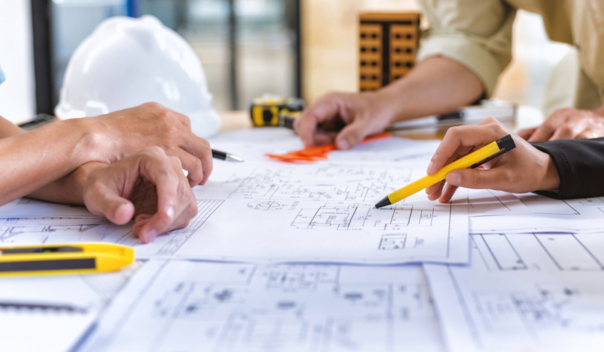 image showing hands of 3 people working on site plans