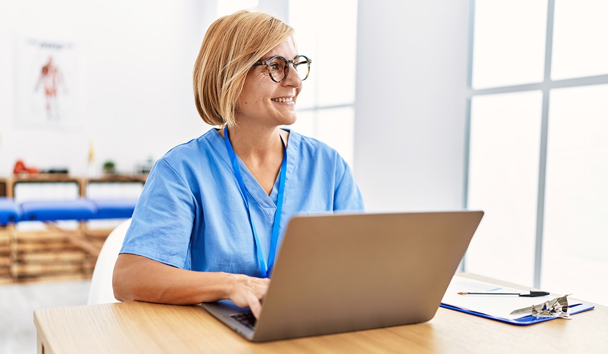 smiling nurse sitting at her desk with laptop