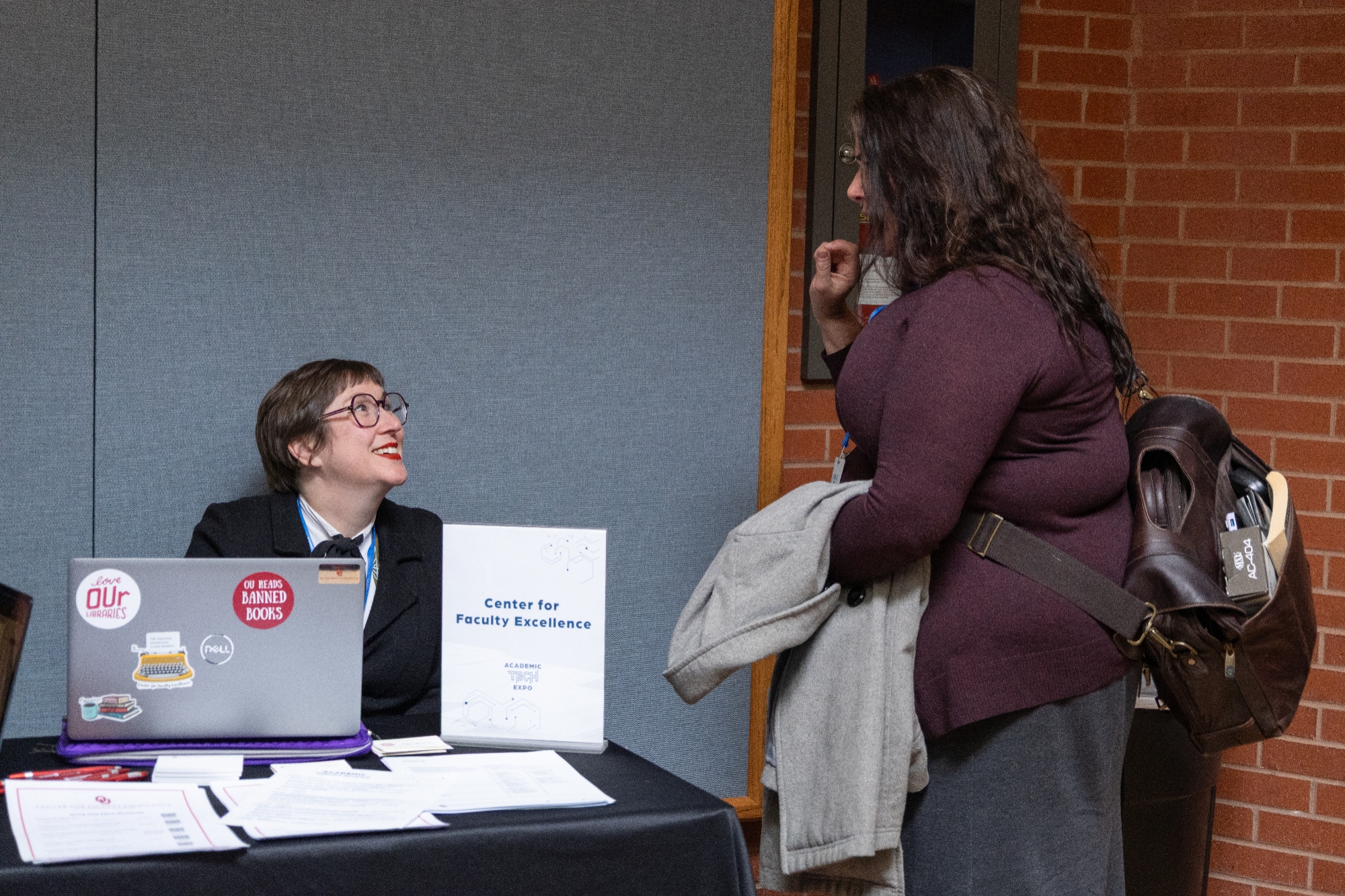 A person smiling and talking to someone standing up.