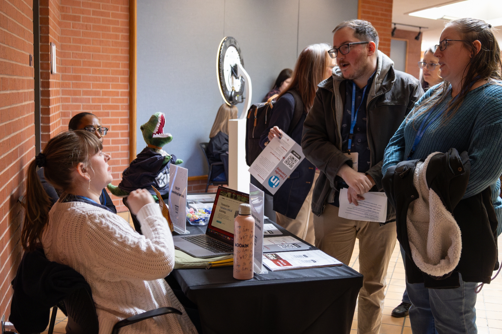 Two people talking to another person at a table.