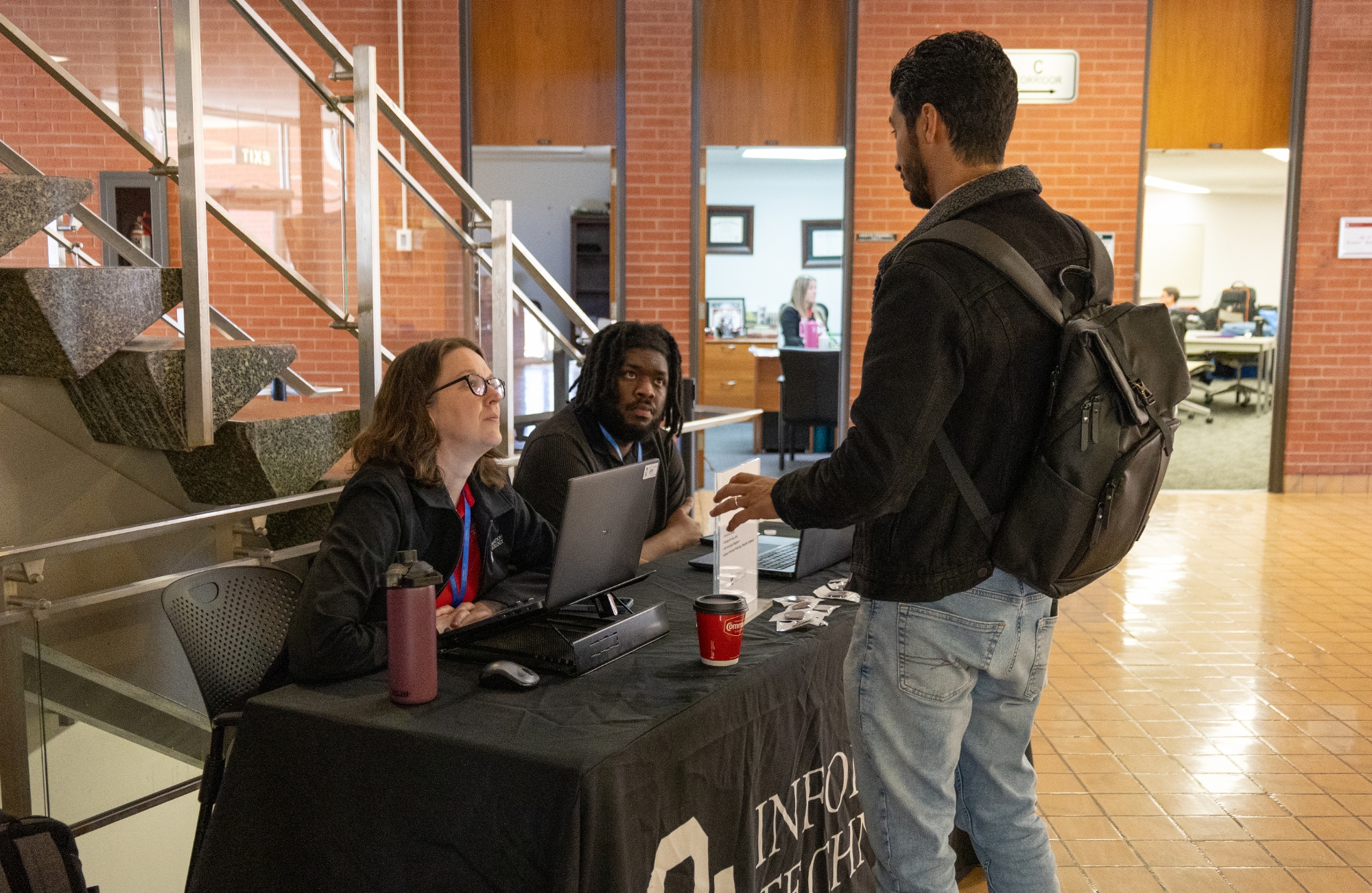 A person talking to two people at a table at the conference.