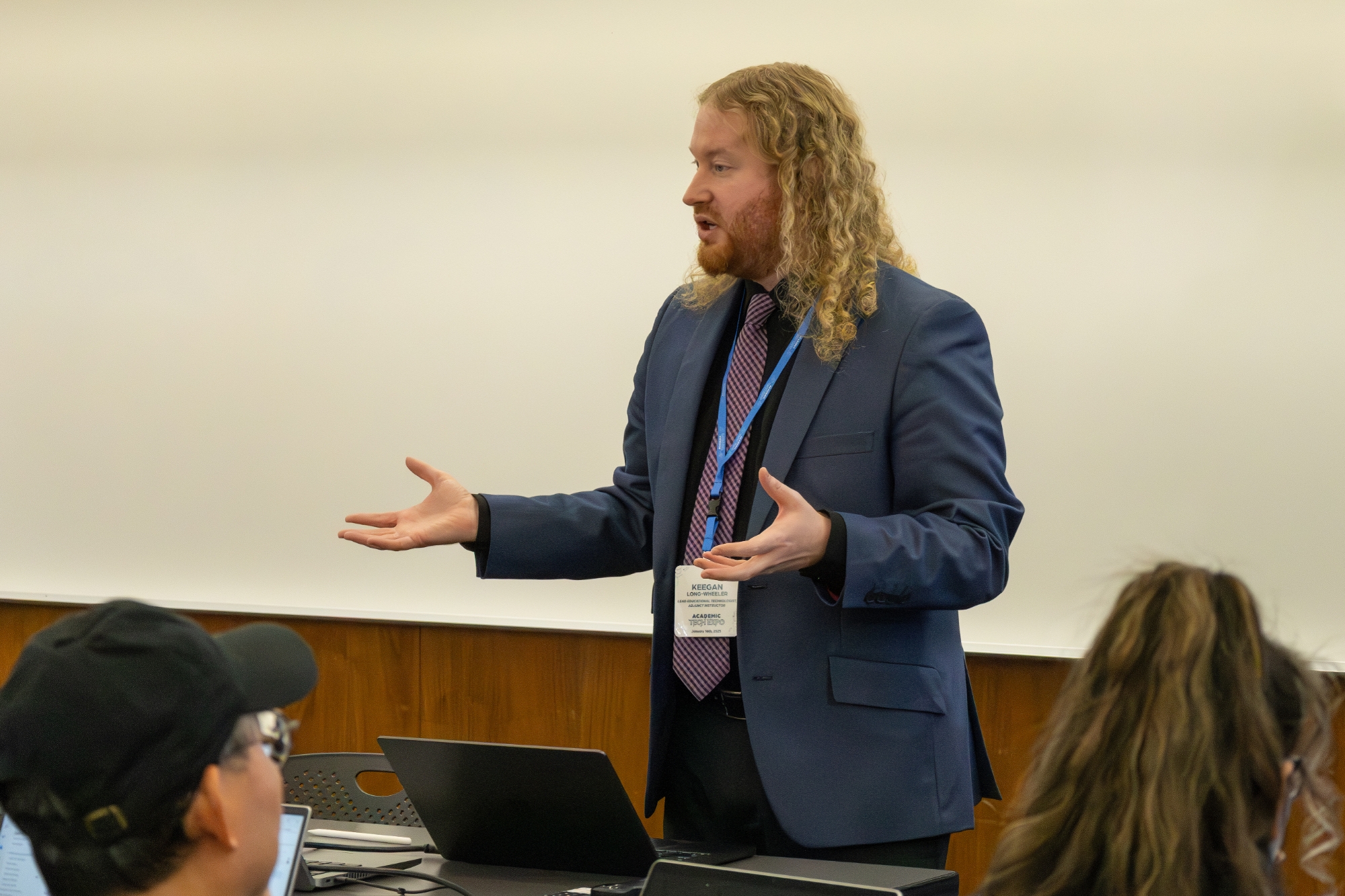 A person standing with hands out talking to a group.