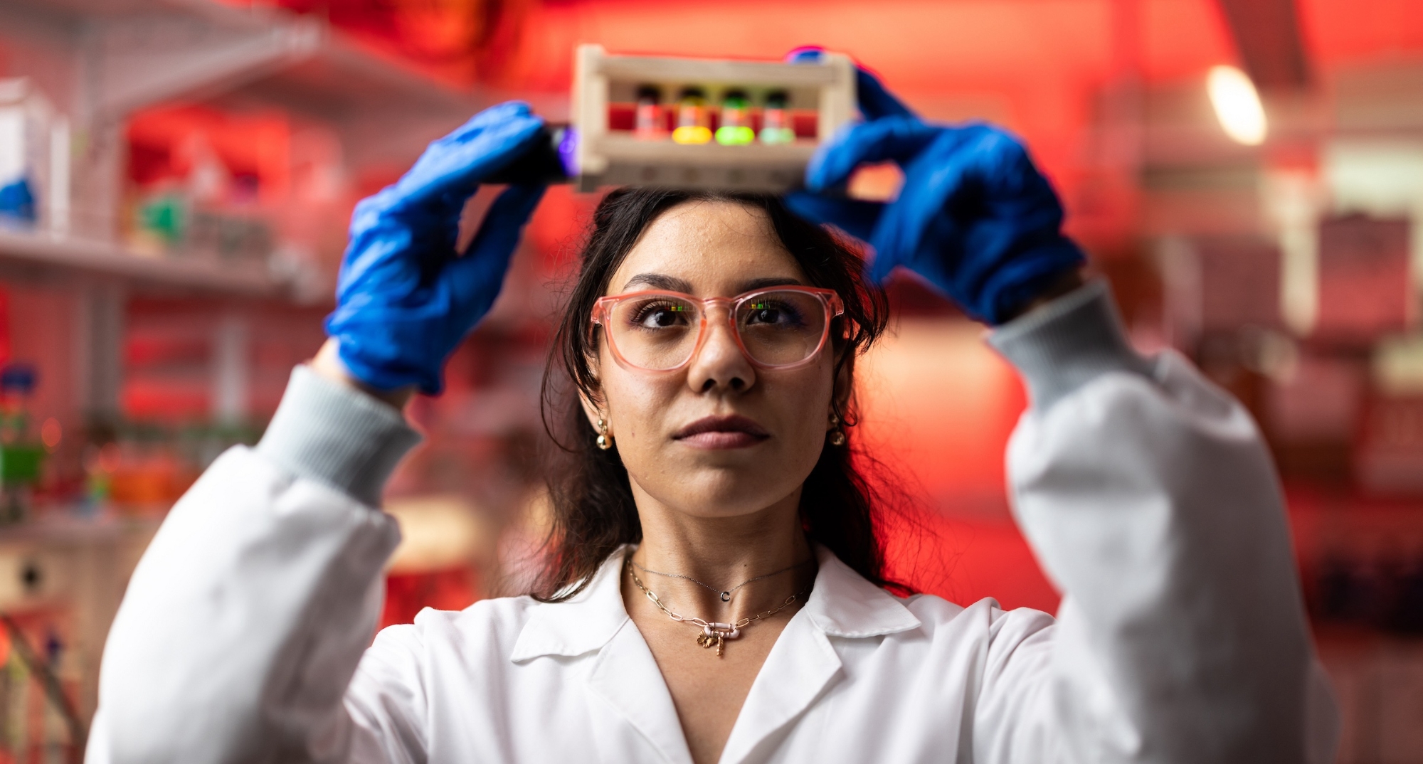 An OU researcher wearing safety googles and a mask works with laboratory equipment.
