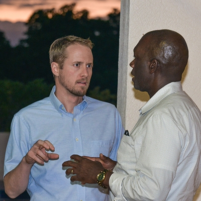 Two men standing in front of a window having a mentoring session.