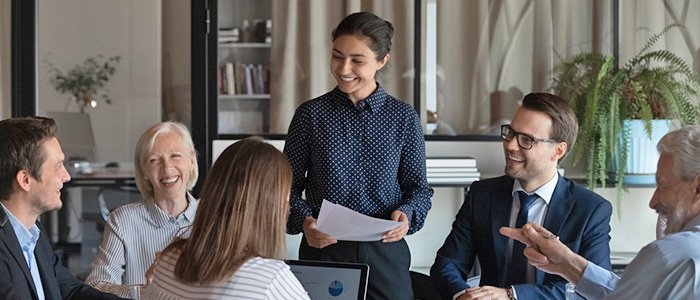 young professional woman giving a presentation to 4 co-workers