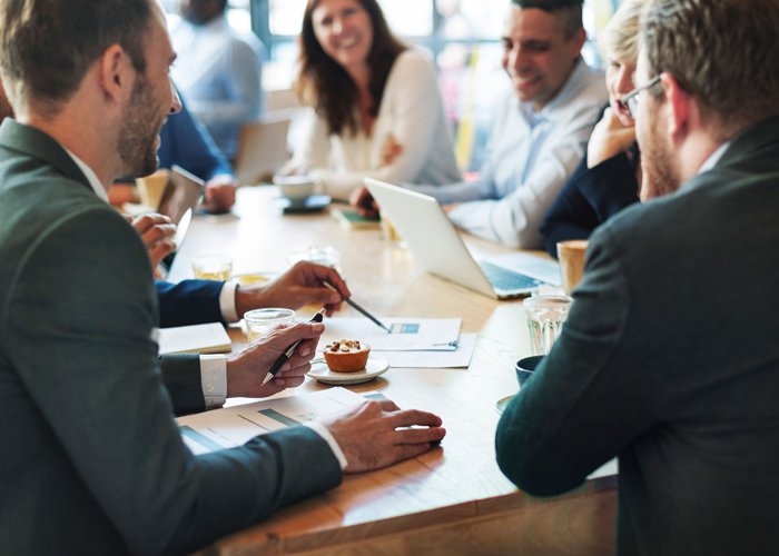Group of business professions sitting around a table smiling during a team meeting