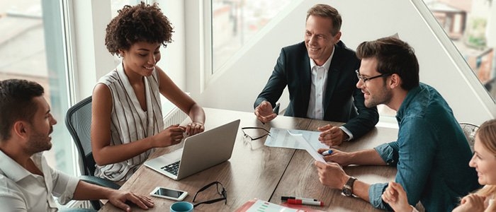 four business professionals sitting around a table and discussing a project