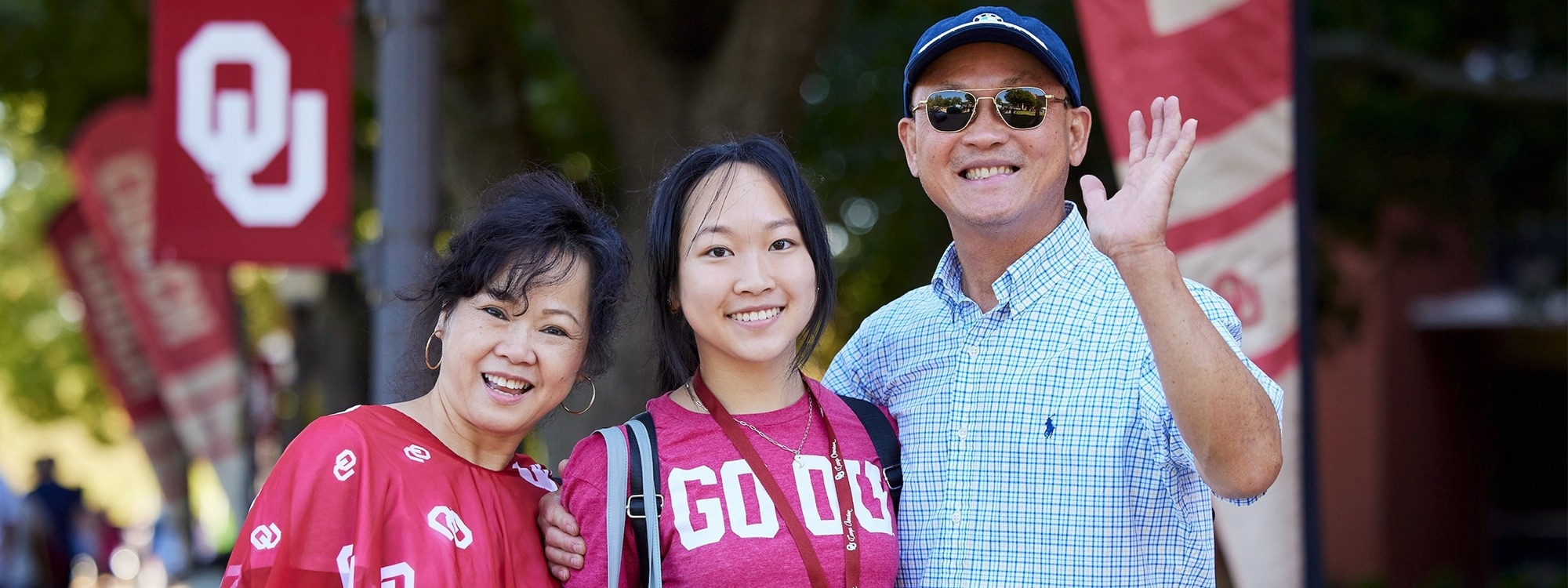 A mother, daughter, and father smiling at family weekend.