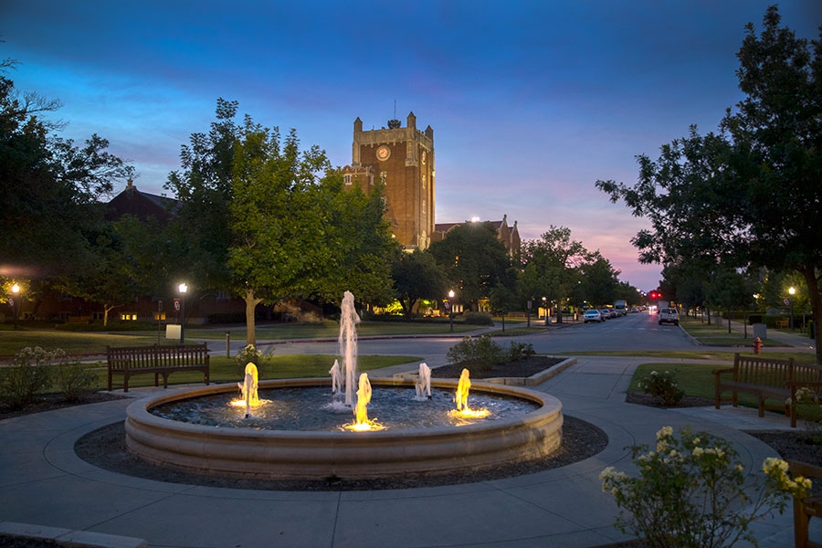 The Oklahoma Memorial Union at dusk, with a water fountain in the foreground.