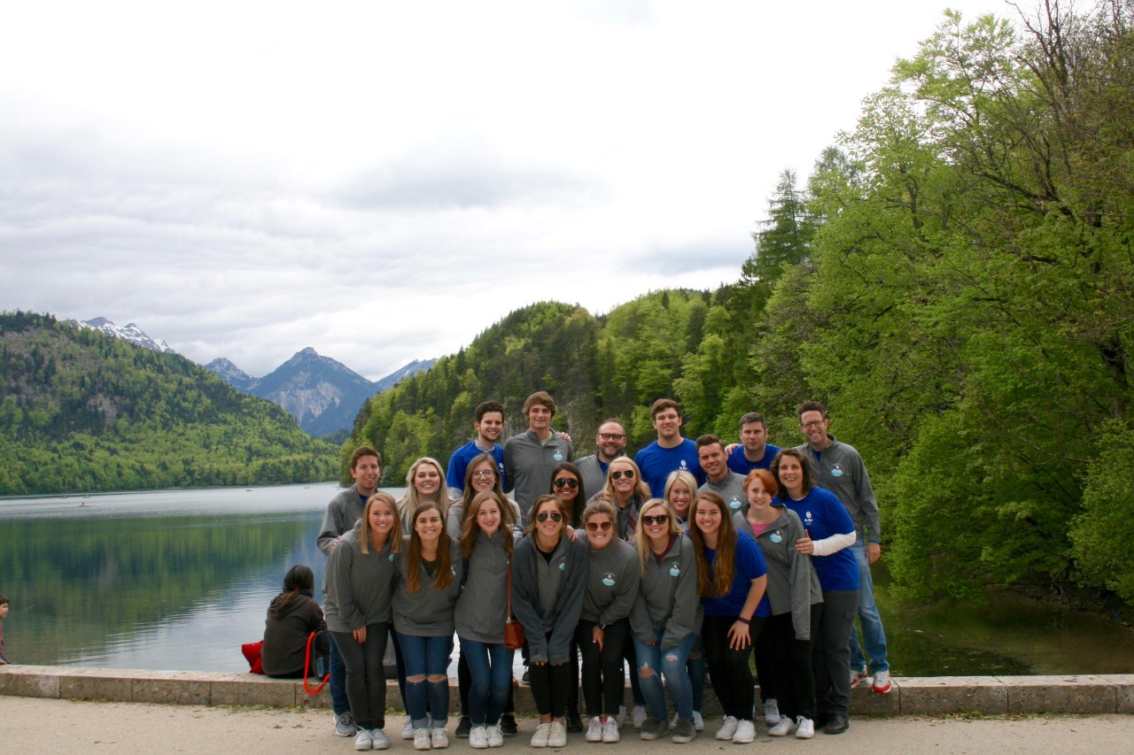 PLC student alumni group photo in Germany with a lake and mountains behind them.