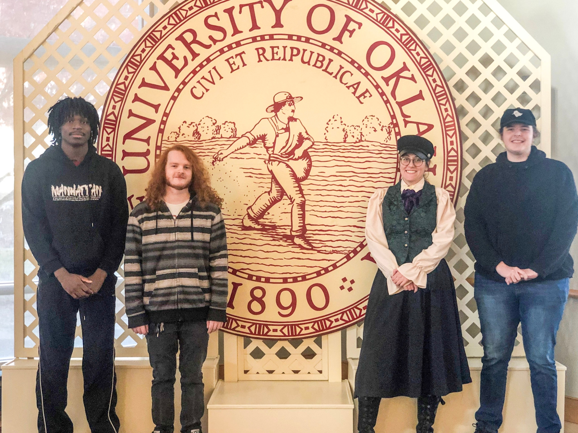 All four of OUPI's McNair Scholars standing in front of the OU seal.