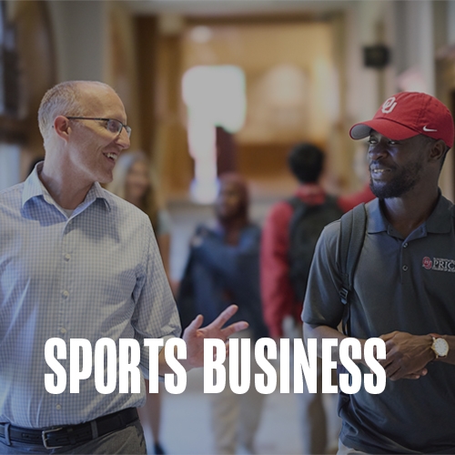 A professor and a student walking through the hallway. A text overlay reads: Sports Business.