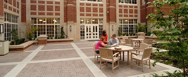 Students gather around a table in the Dodson courtyard at Price College of Business