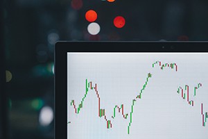 The photo shows a stock market candlestick graph on a computer screen. 