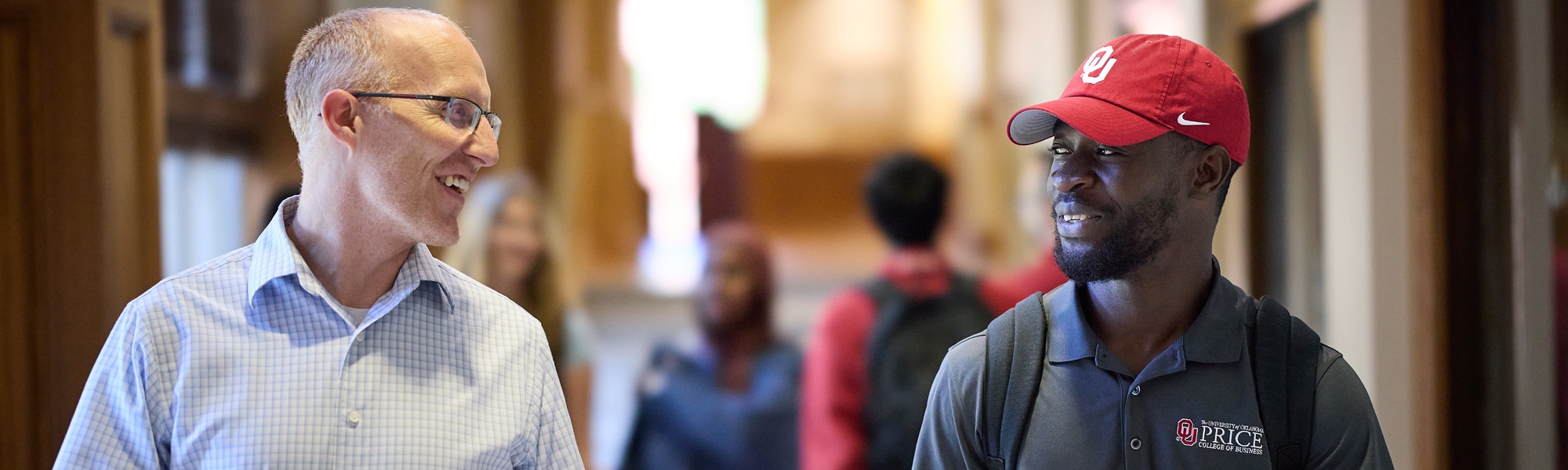 A professor and a student engaging in a conversation in the hallway.